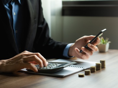 Mann tippt Zahlen in einen Taschenrechner: Wir führen Berechnungen durch, um den optimalen Ratenkredit für Sie zu ermitteln.