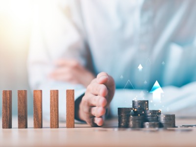 Hand trennt Holzstäbe von einem wachsenden Geldhaufen: Ein Zinssicherungskonto bei uns sichert Ihre Zinsen langfristig ab.