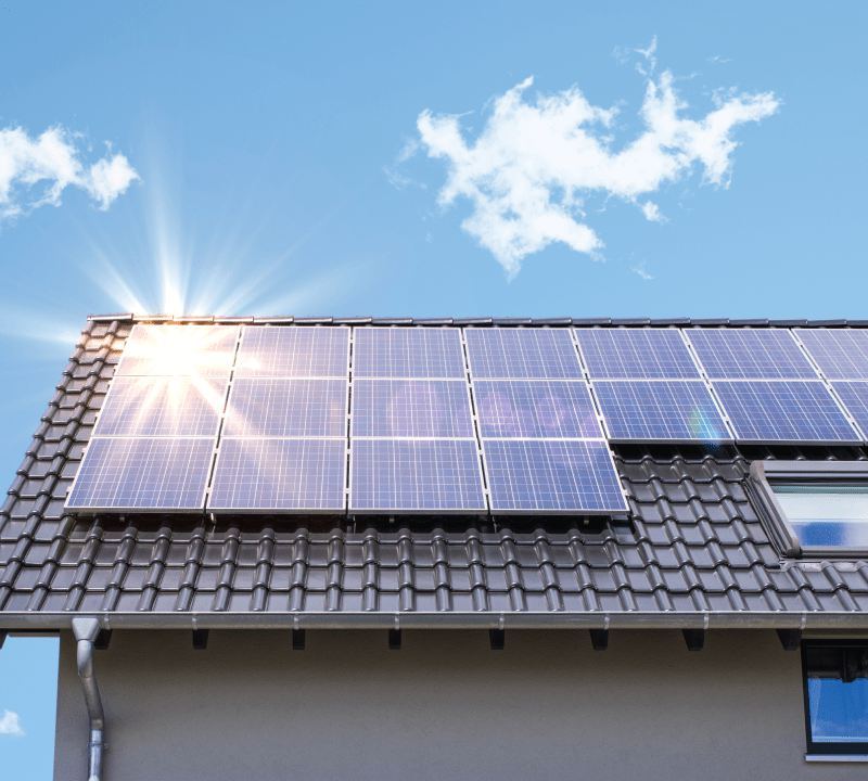 Photovoltaikanlage auf einem modernen Gebäude, reflektiert die Sonne. Beispiel für Projekte, die durch unsere Klimadarlehen für nachhaltige Energie unterstützt werden.