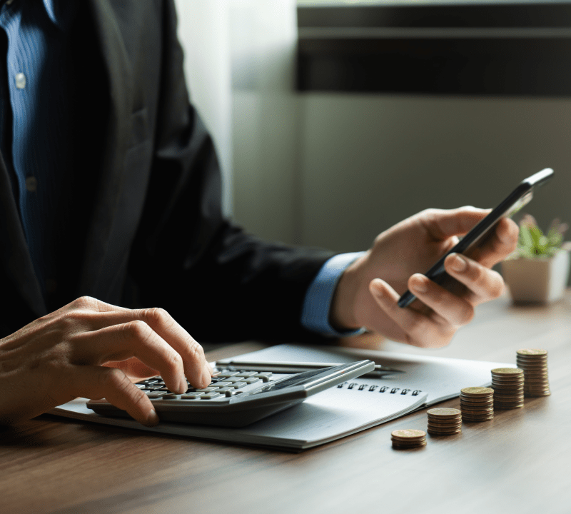 Mann tippt Zahlen in einen Taschenrechner: Wir führen Berechnungen durch, um den optimalen Ratenkredit für Sie zu ermitteln.